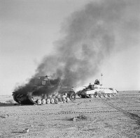 一輛英國坦克路過一輛被擊毀的德軍坦克