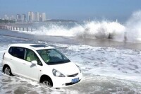 青島 7月10日，巨浪“跨過”堤壩湧向街道。